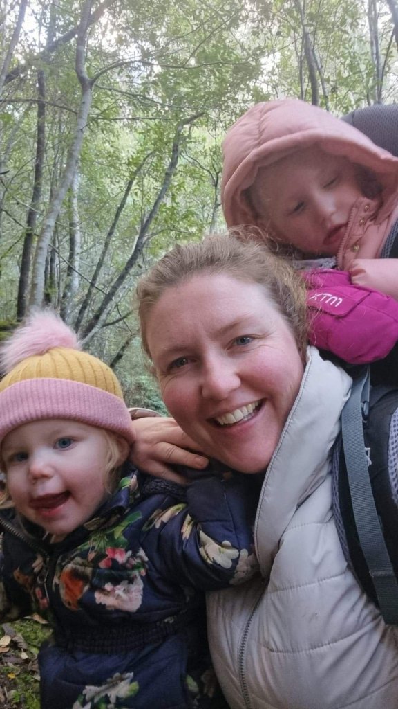 Mummy L poses with a wriggling Miss under 2yo in her arms and a patient Miss 4yo on her back.