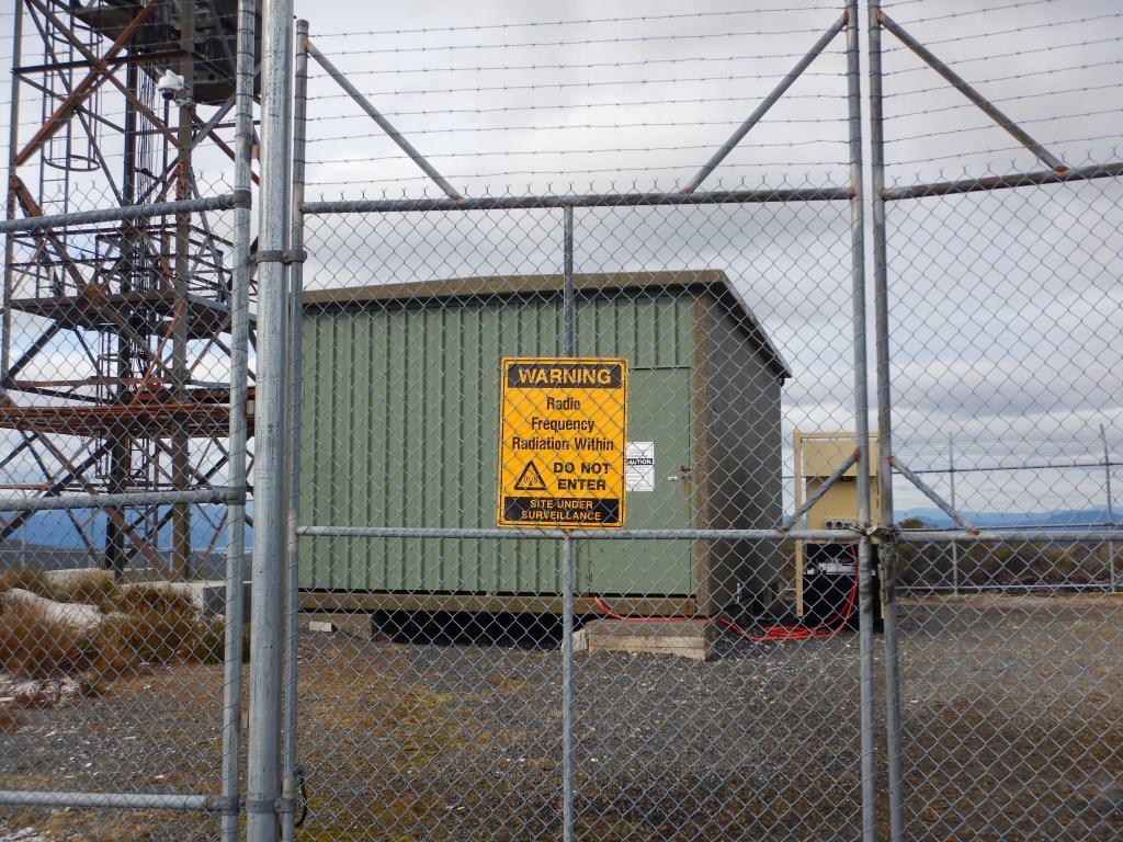 a yellow warning sign reads "warning, radio frequency radiation within. DO NOT ENTER. Site under surveillance. 