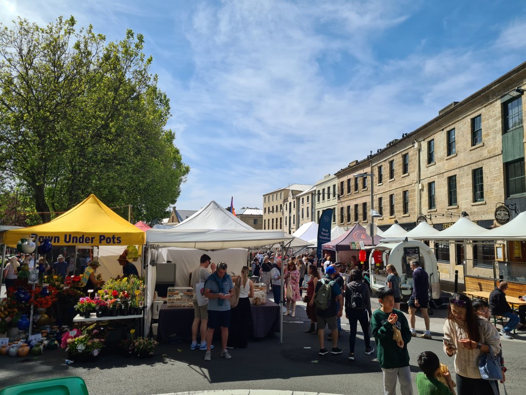 Crowds form around the gazebos and sandstone buildings of Salamanca Markets